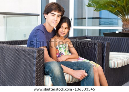 Good looking and loving Brother and Sister sit together on a patio at a luxury hotel