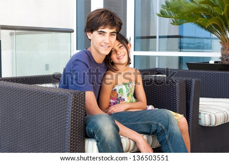Good looking and loving Brother and Sister sit together on a patio at a luxury hotel