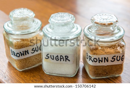 White and brown sugar in jar on wooden table