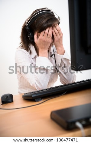 Young depressed business person (call center employee) with headache at computer