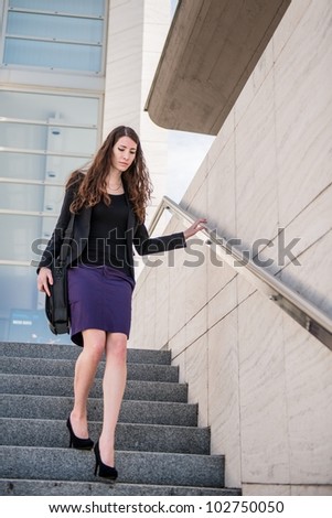 Young business woman in hurry - walking on stairs with notebook bag
