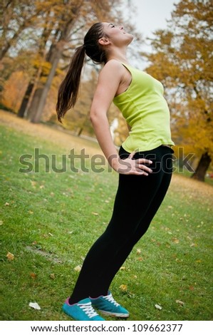 Woman performs stretching before sport outside