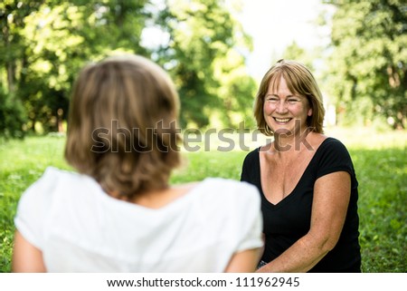 Senior woman chatting with her adult daughter outdoor in nature