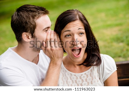 Young man whispering to woman (girlfriend) - surprise expression