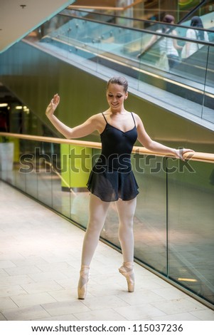 Ballet dancer dancing in modern business premises at escalator