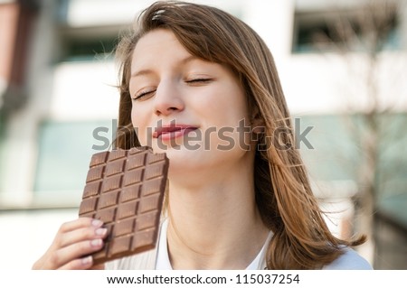 Portrait of young beautiful woman eating chocolate - lifestyle outdoor image