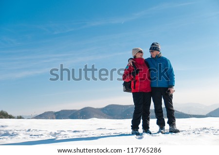 Senior couple outdoor portrait- happy mature man and woman in winter snowy landscape