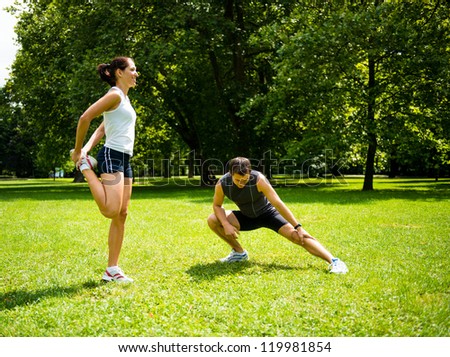 Young couple exercising and stretching muscles before sport activity - outdoor in nature