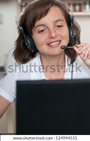 Young business person with headache working at home and calling (headset on head)