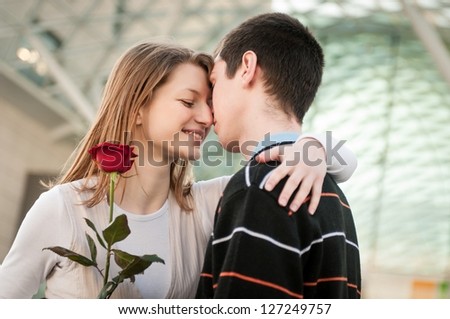 Young man handing over a flower (red rose) to woman - intimate moment