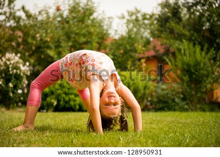 Sporting on grass - smiling little child making bridge outdoor in backyard