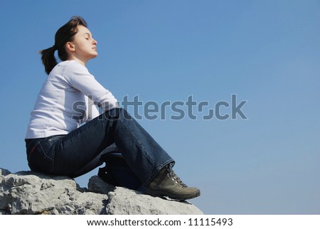 Young attractive woman with face turned against sun in mountains