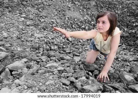 Young woman needs help and stretches her hand from rocky hole