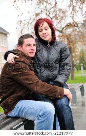 Woman sits on knees of man outdoors - romantic scene