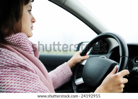Young business woman driving car in rain (focus on face)