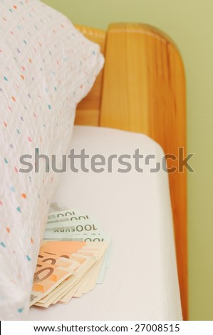 Money laid on bed under pillow