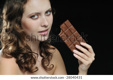 Young beautiful nude sensual woman holding milk chocolate isolated on black background