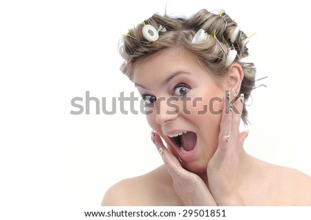 Young beautiful surprised woman with hair rollers in curls isolated on white
