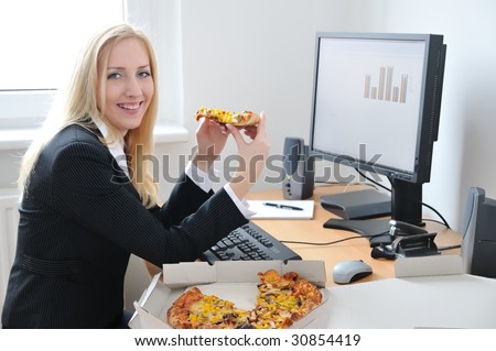 Young smiling business person on work place eating pizza