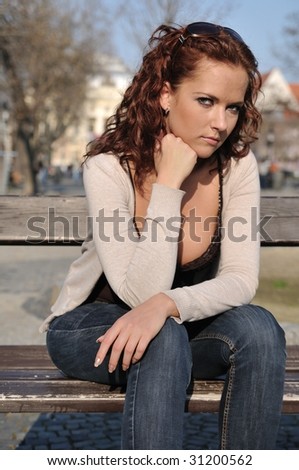 Young depressed woman (person) siting on bench in street
