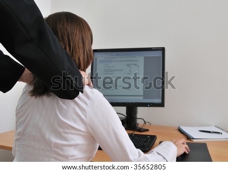 Business working person (woman) behind computer receiving neck massage from colleague (rear view with hands)