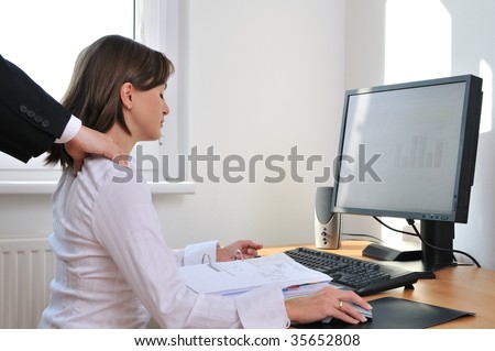 Business working person (woman) behind computer receiving neck massage from colleague (only hands visible)
