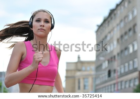 Person (young beautiful woman) listening music running (jogging) in city street