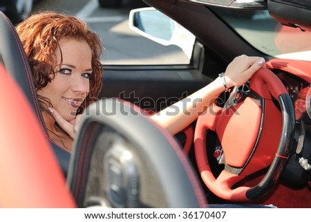 Young beautiful smiling woman sitting in sport car - red interior detail