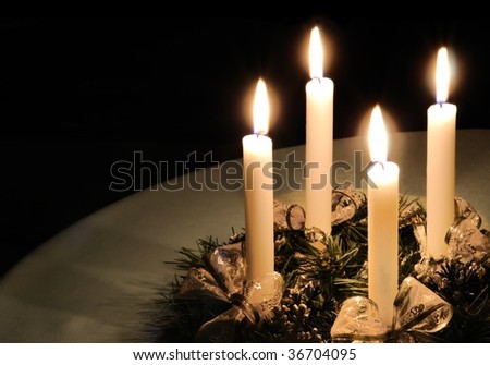 Christmas advent wreath with burning candles laid on table with black background
