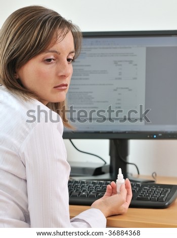 Detail of sad business person (woman) after applying eye drops on workplace - computer monitor in background