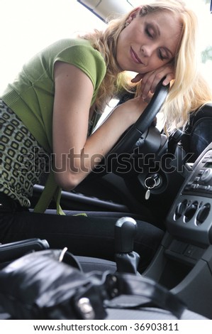 Young beautiful blond woman sleeps in car on steering wheel - detail portrait