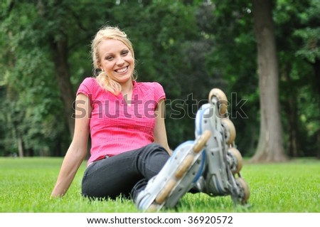 Young smiling woman relaxing in green grass after roller blading