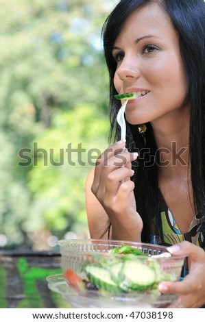 Young beautiful woman having lunch break and eating salad outdoors in park