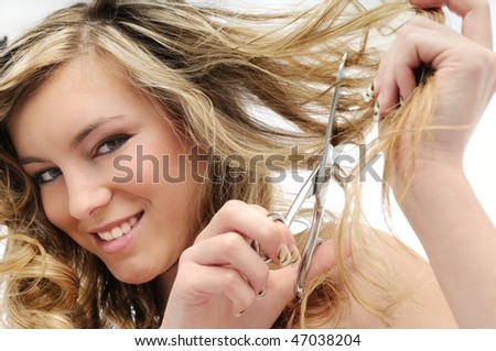 Young smiling beautiful woman cutting her hair with scissors - detail