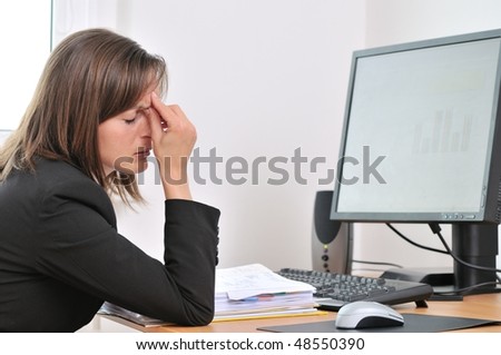 Young business woman with headache and tired closed eyes sitting at computer in workplace