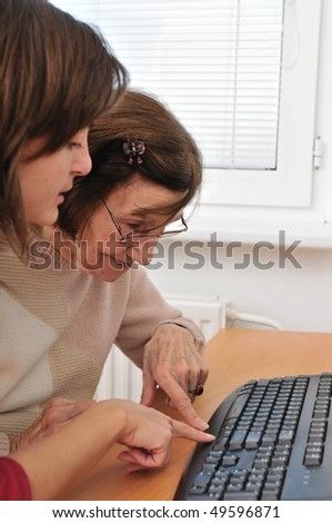 Young woman teaches her grandmother work with computer - senior lifestyle