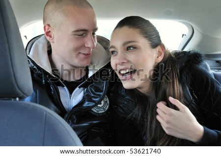 Young couple dressed in black having fun in car - sitting on back seats