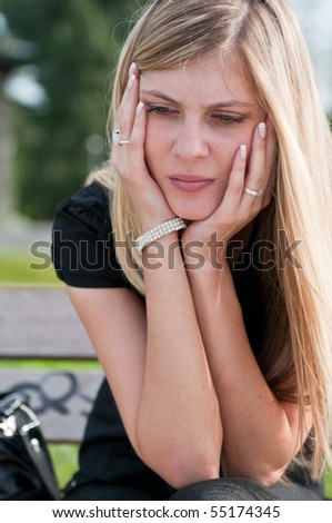 Young worried beautiful woman siting on bench - head in hands