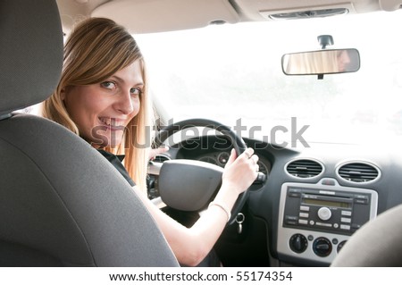  Portrait of young smiling woman siting behind steering wheel inside car