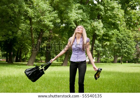 Young woman enjoying life outdoors - spinning around and holding bag and shoes
