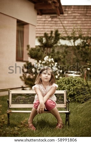 Girl having big problems - sitting on bench in backyard with family house behind