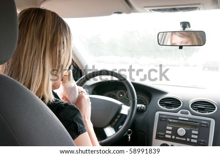 Young beautiful woman driving car and eating fast food - rear view