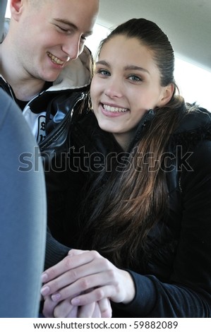 Young couple dressed in black having fun in car - sitting on back seats