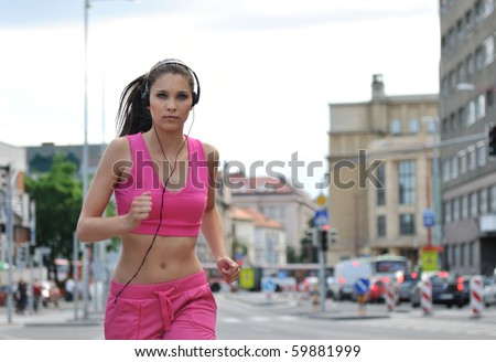Runner (young beautiful woman) training in street with (traffic background - cars and buildings)