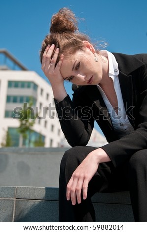 Young worried business woman siting outdoors - head in hand