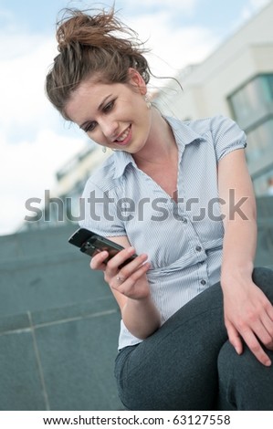 Young beautiful laughing woman reading message on mobile phone