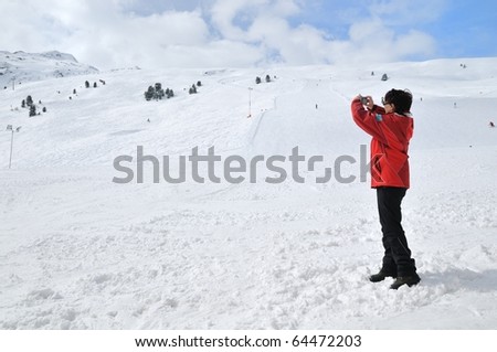 Senior woman taking picture with camera in mountain winter snow landscape