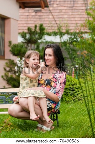 Mother and daughter spending time together in garden - family house in background