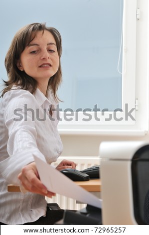 Business person reaching hand and taking paper from printer on workplace - detail