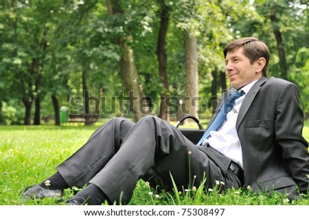 Senior people series - mature business man siting on grass and relaxing in nature